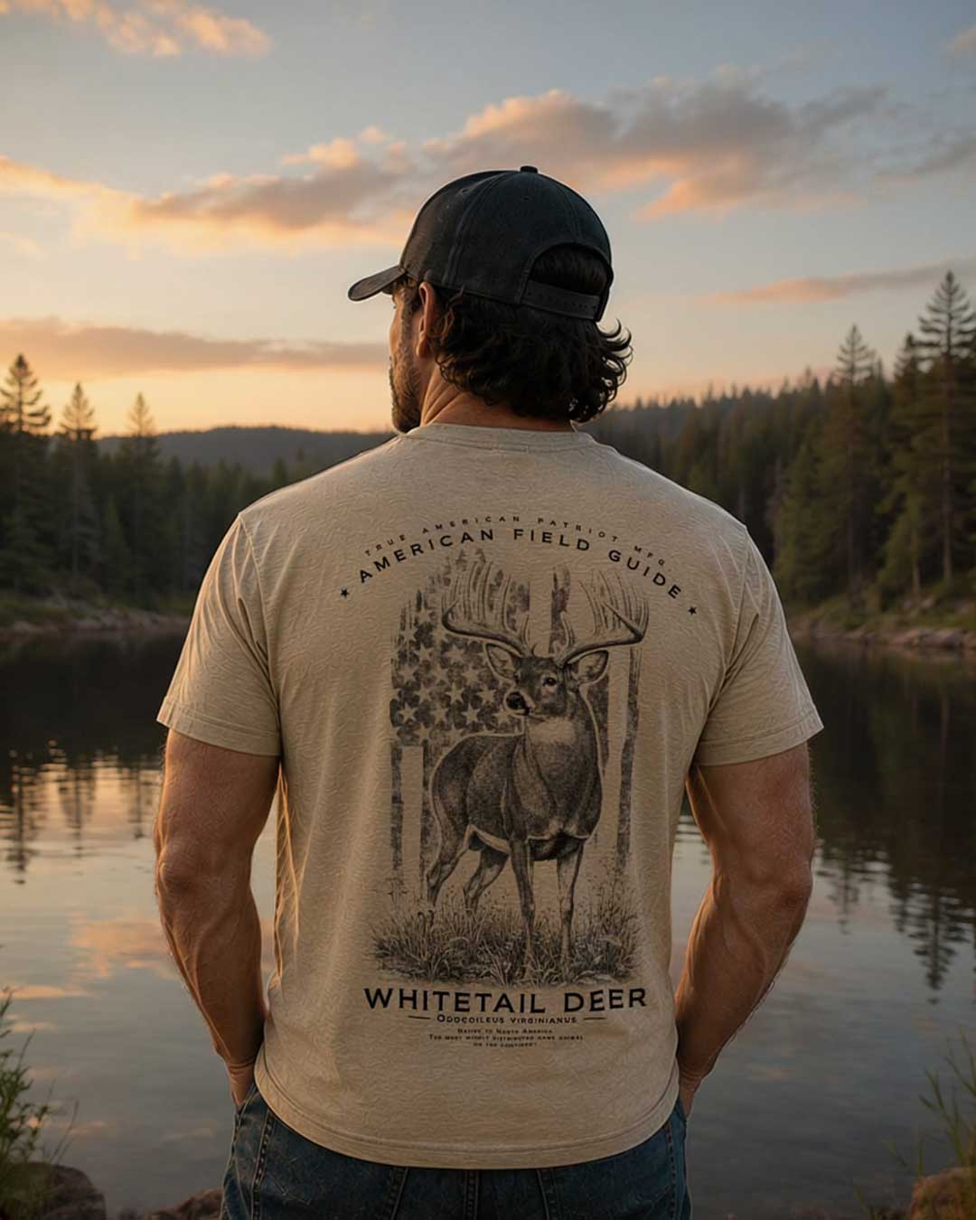 Model wearing the American Field Guide Whitetail Deer graphic tee overlooking a mountain lake at sunset. Premium outdoor apparel by True American Patriot MFG.