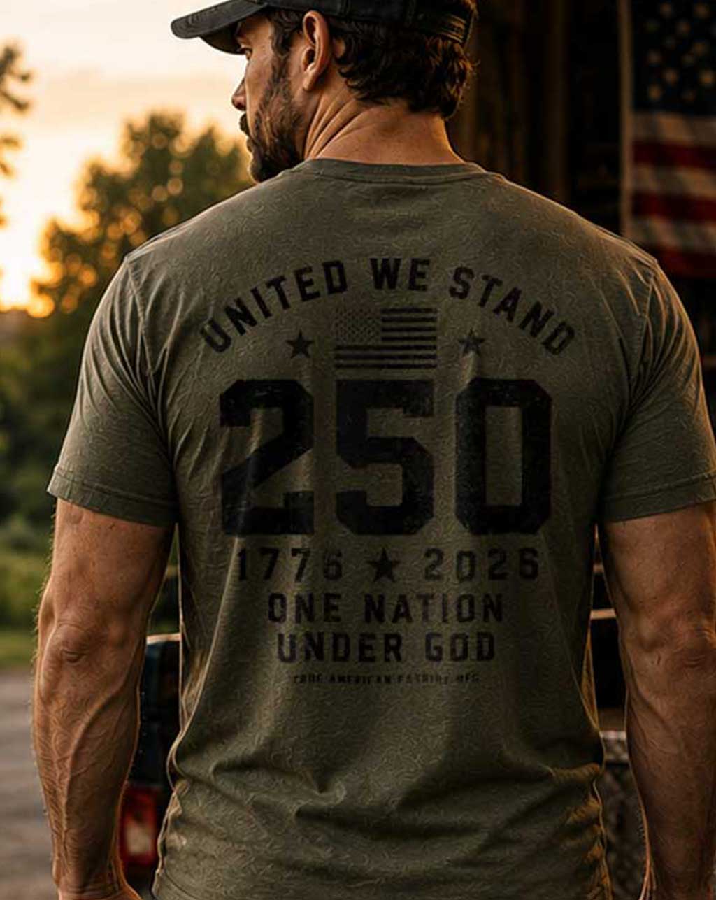 Man wearing a green t-shirt with text on the back, standing outdoors with an American flag in the background.