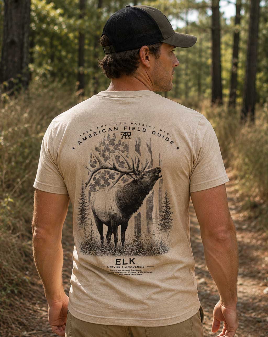 Model wearing the American Field Guide Elk Tee in Heather Tan by True American Patriot MFG. outdoors on a wooded trail.