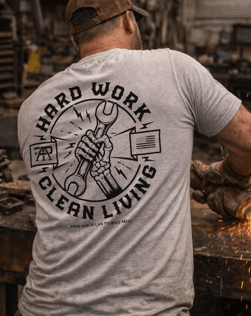 Man using a grinder on a workbench wearing a True American Patriot Mfg Hard Work Clean Living Tee