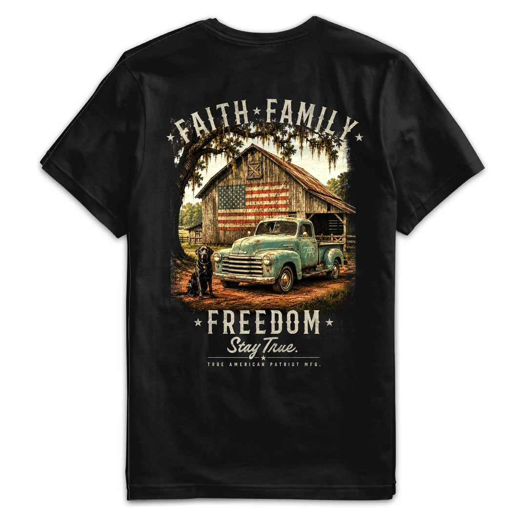 Back of the Faith, Family, Freedom Tee by True American Patriot MFG featuring a vintage pickup truck, American flag barn, black Labrador, and Stay True artwork on a black premium t-shirt.