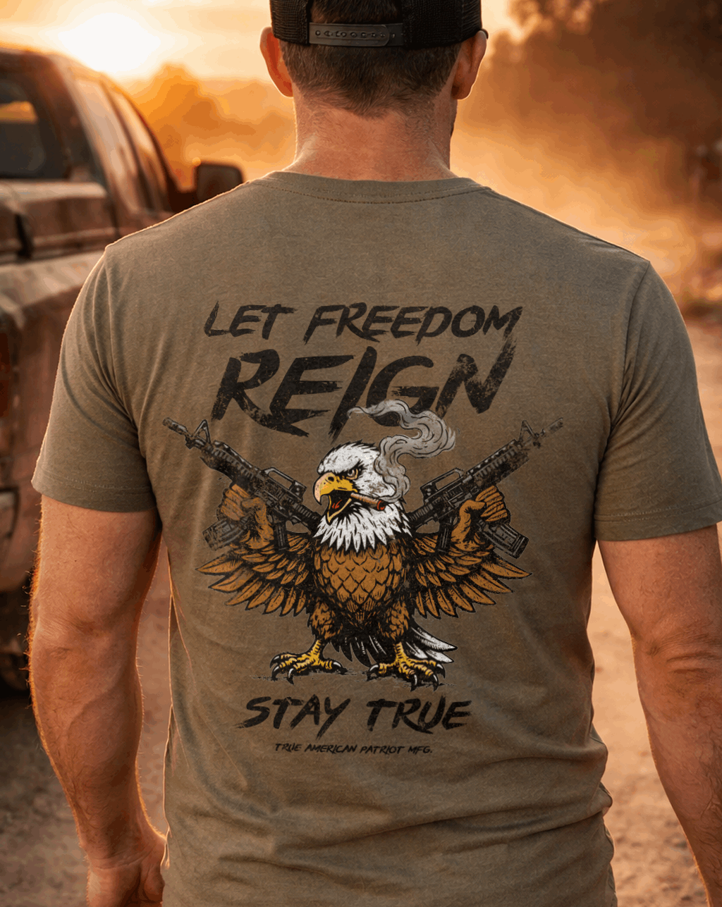 Man wearing Military True American Patriot MFG Let Freedom Reign T-Shirt next to tuck with sunset background