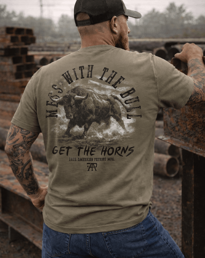 Man wearing a True American Patriot Mfg Mess With The Bull Get the Horns Tee in a steel yard