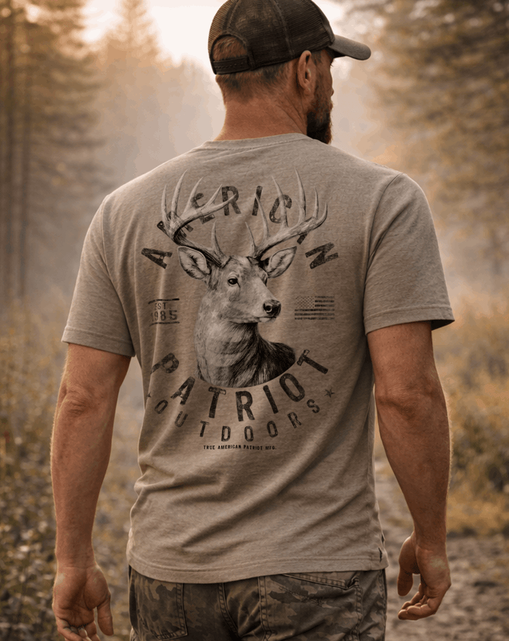 Man wearing a True American Patriot Mfg Whitetail Buck American Outdoors Tee walking through the woods