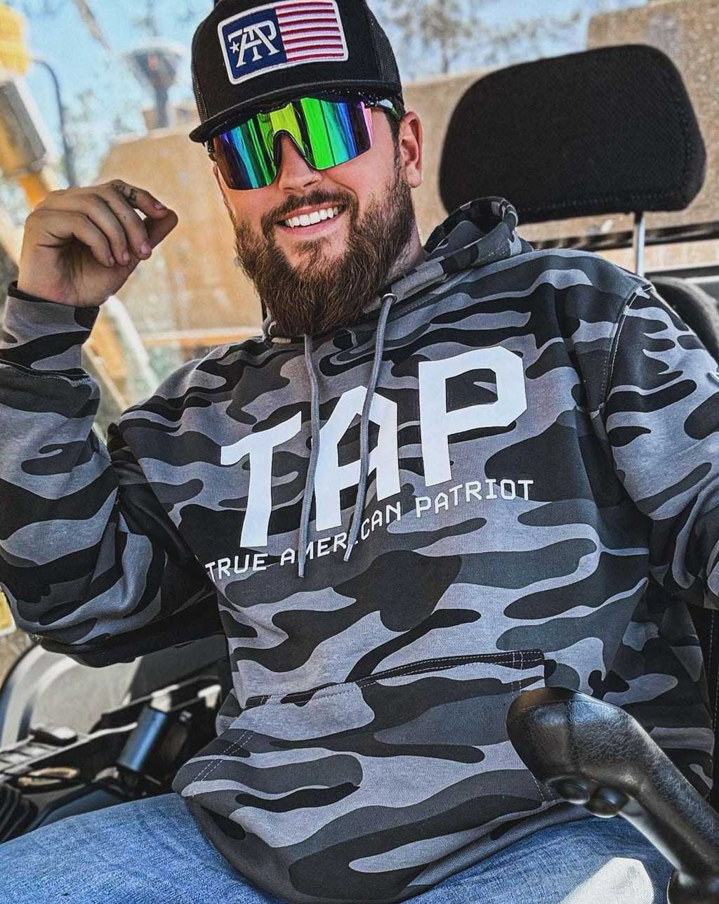 Man wearing a TAP camouflage hoodie at a construction site