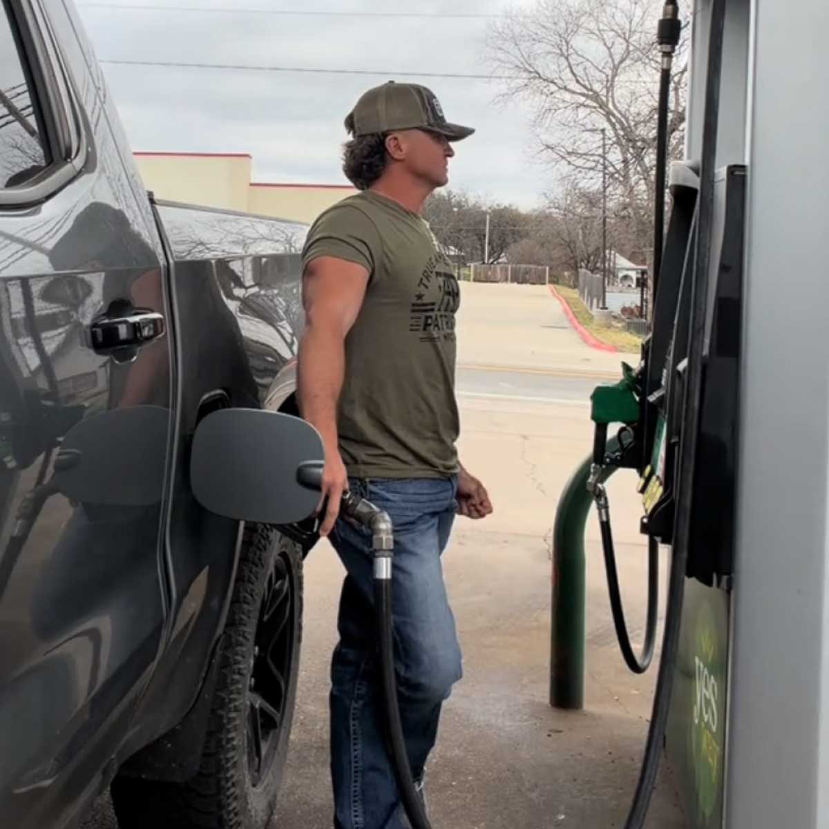 Man wearing a TAP T-shirt beside his truck at a gas station